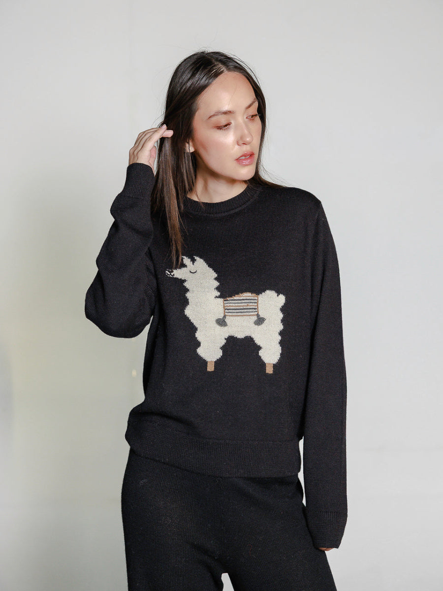 black alpaca knitted sweater with white llama design, worn by a model on a white background