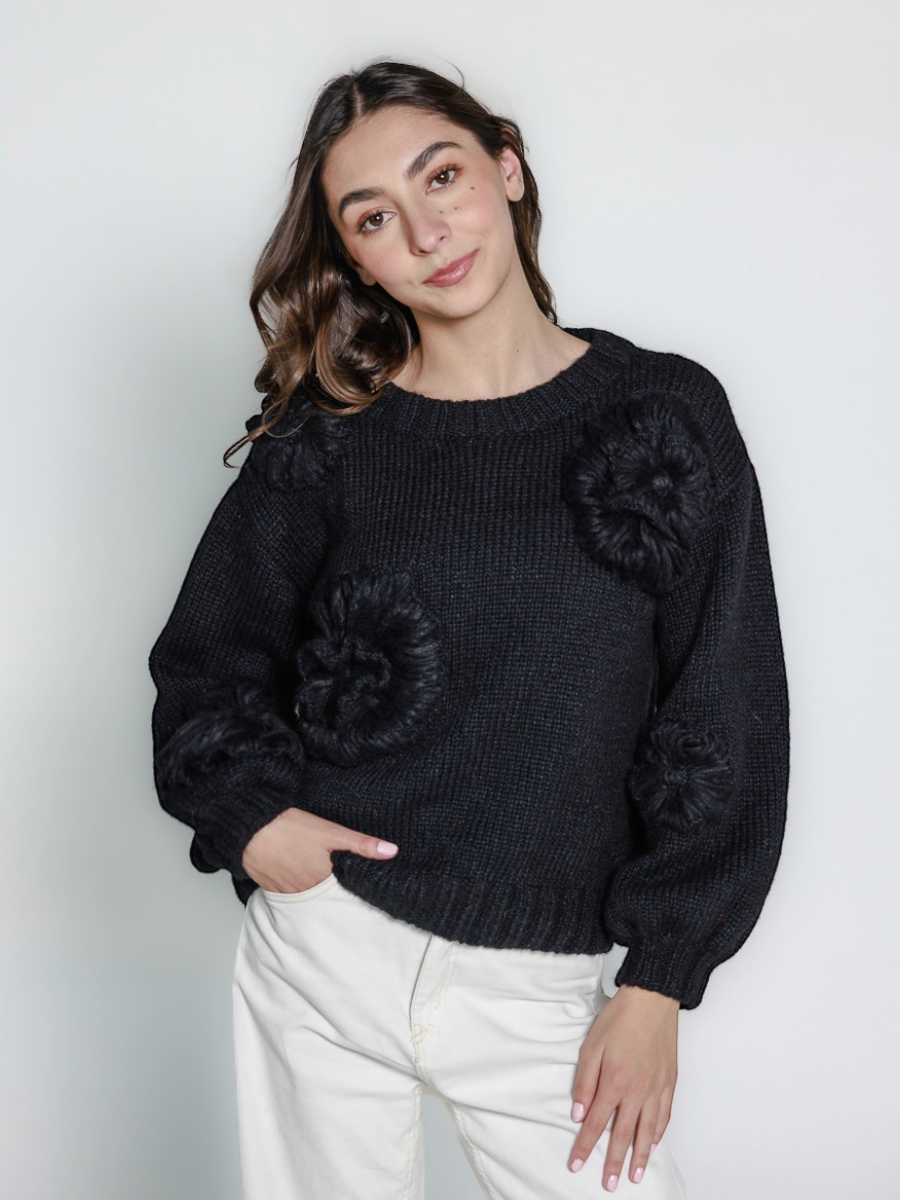 black llama hand-knitted sweater with floral embellishments, worn by a model against a white background