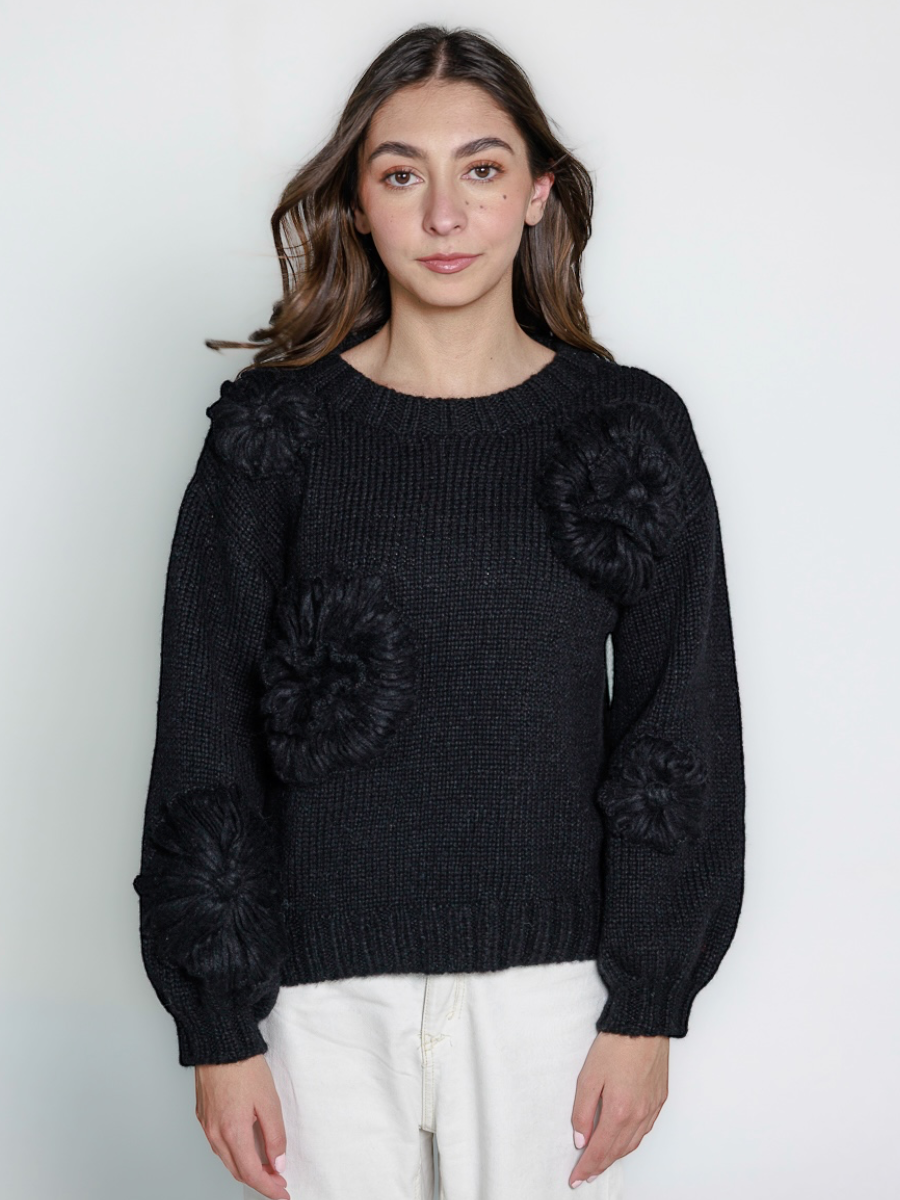black llama hand-knitted sweater with floral embellishments, worn by a model against a white background