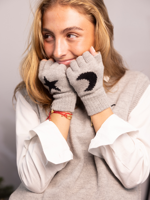 Woman wearing a grey knitted gloves with a design of a black star and a moon 