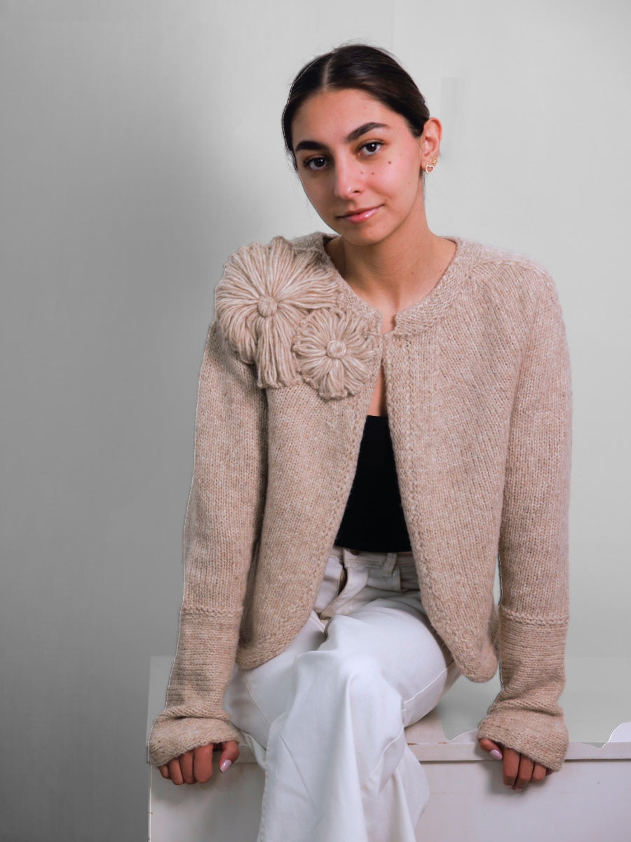 Woman wearing a beige knitted jacket with a large flower. Fall cardigans llama wool