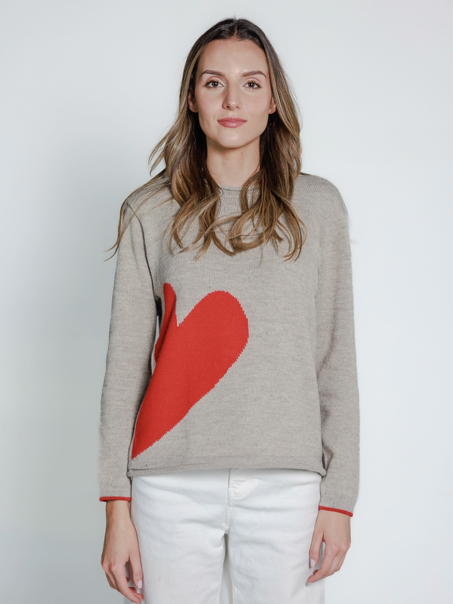 light grey alpaca sweater featuring an oversized red heart motif on the side, worn by a model
