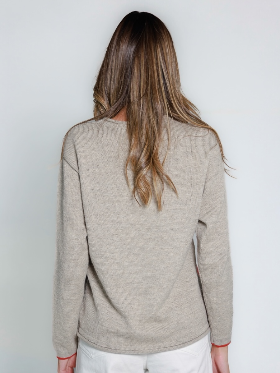 light grey alpaca sweater featuring an oversized red heart motif on the side, worn by a model