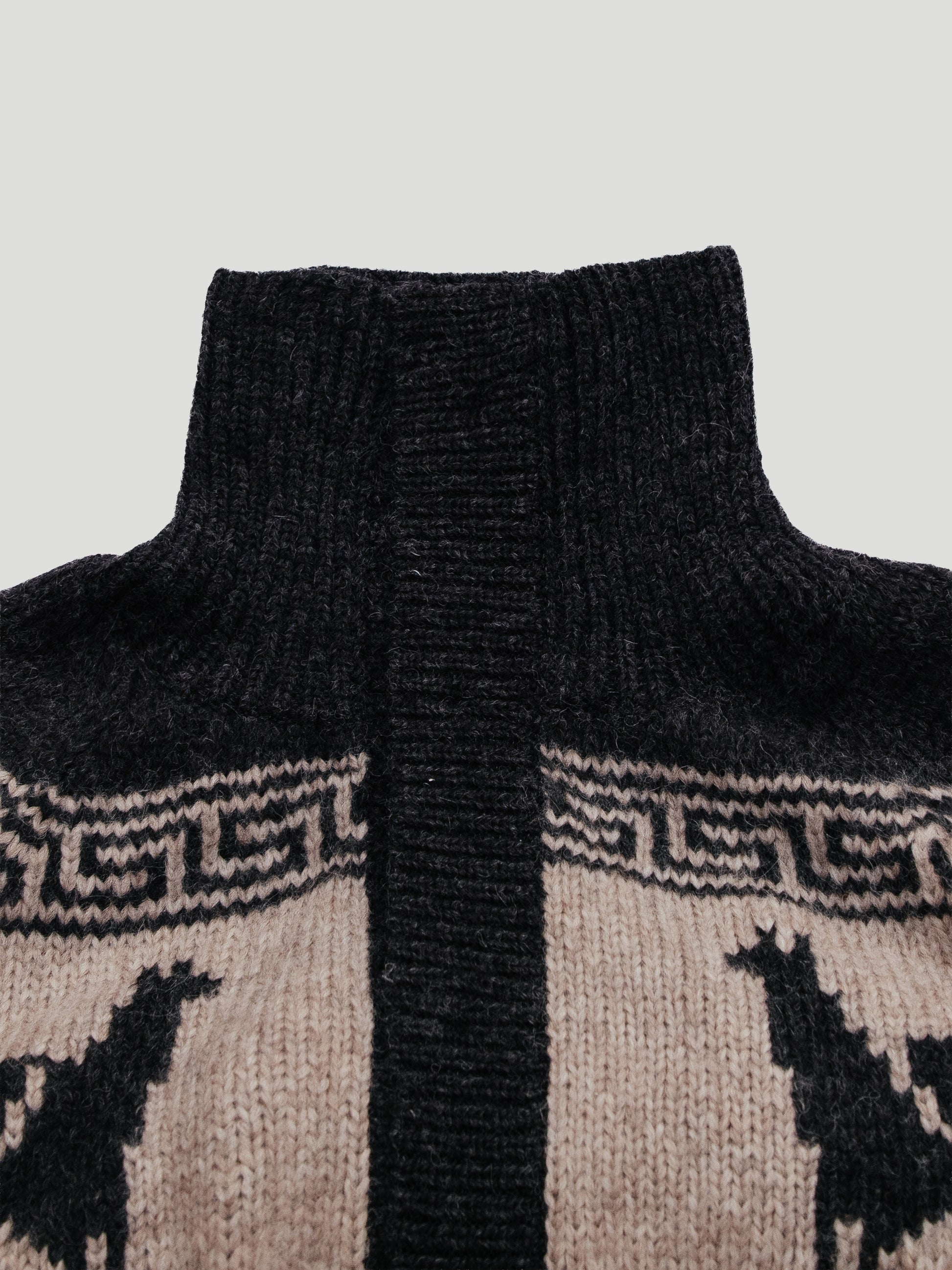Close-up of a sweater with a patterned collar and black turtleneck on a light gray background