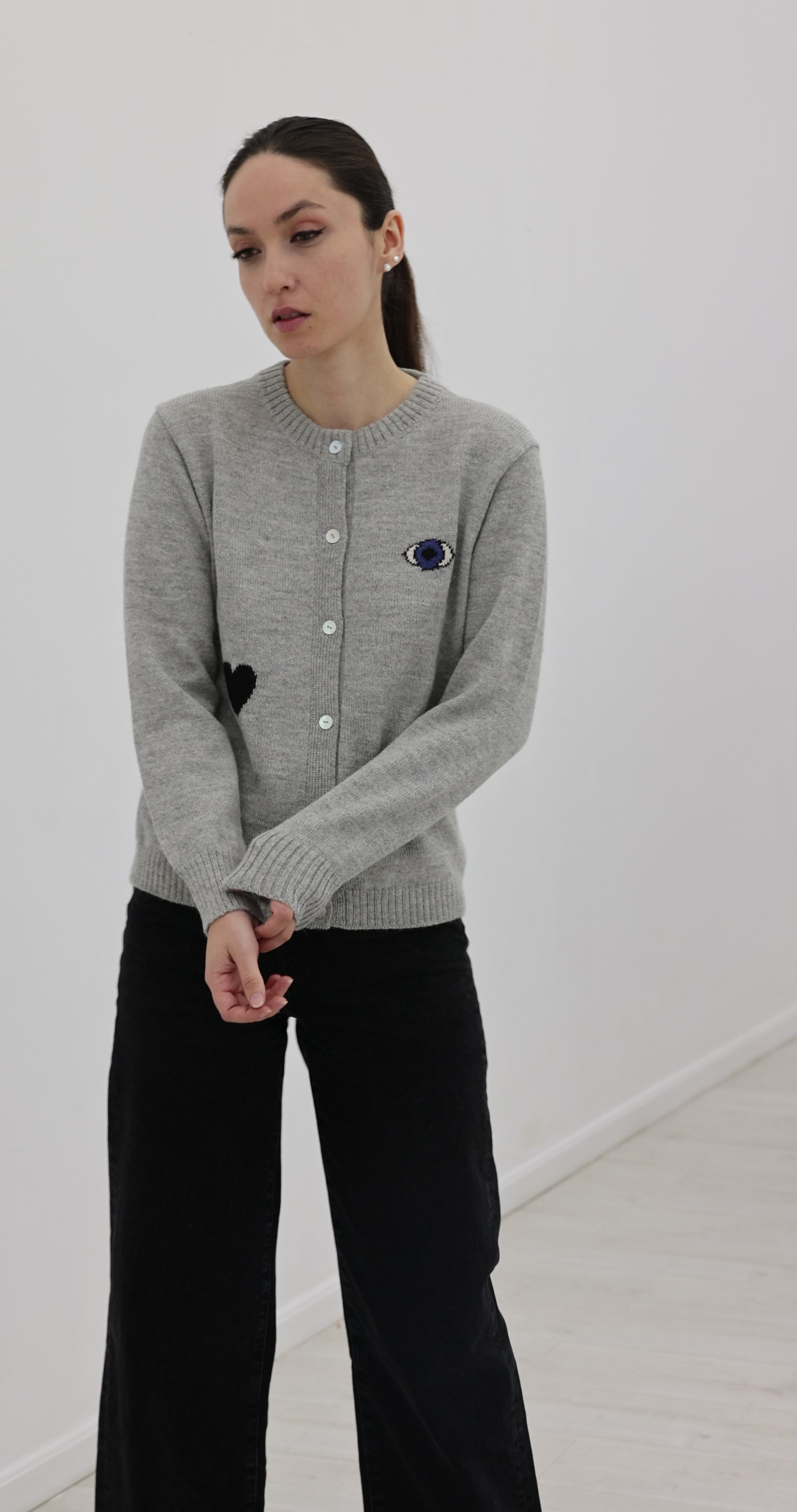 grey button up cardigan decorated with a turkish eye, black heart and a yellow star, worn by a model on plain background