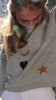 grey sweater decorated with a Turkish eye, heart and a star on a model in city street