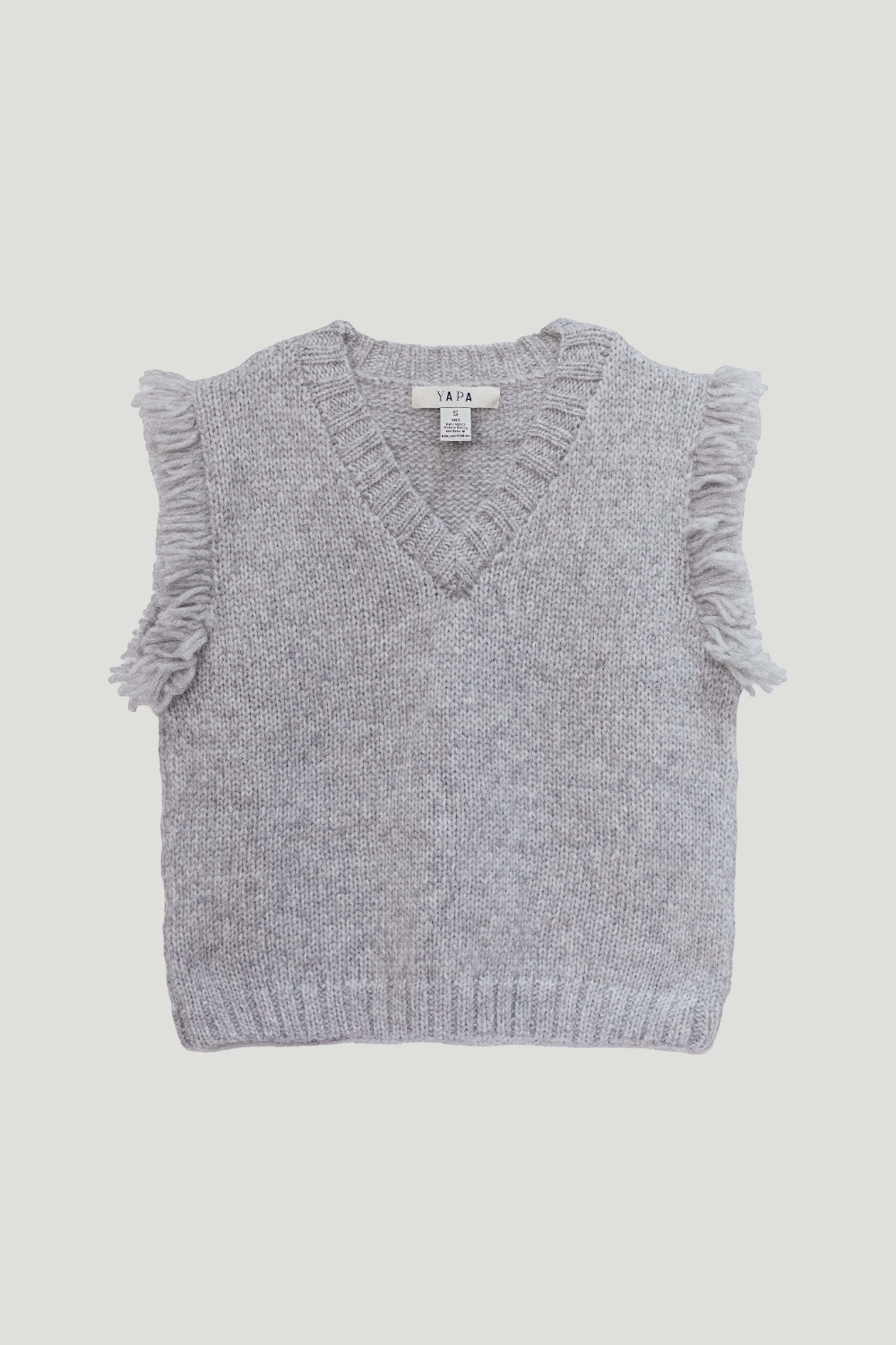 A light gray knit sweater vest with fringed sleeve edges and a V-neck, laid flat against a light gray background. The brand label reads '1974'.