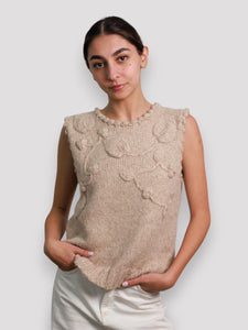 Woman wearing a beige knitted sweater vest.