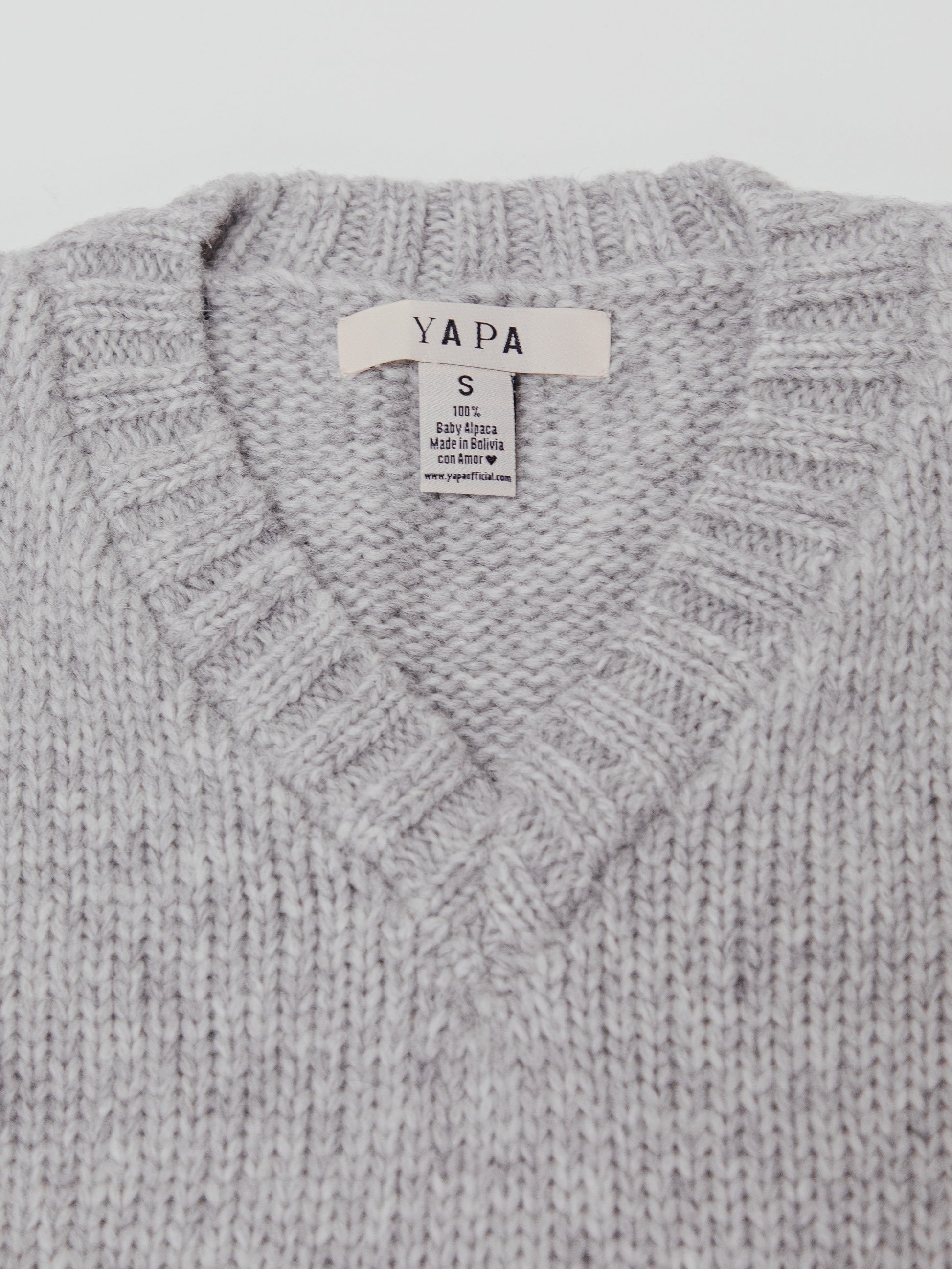 Gray knitted sweater with a visible brand label on a light gray background