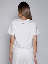 Cargar imagen en el visor de la galería, Person wearing a white t-shirt with YAPA and NY text on the back against a plain background
