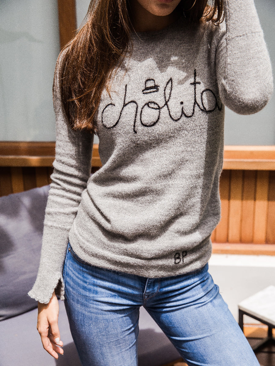 Light grey alpaca sweater featuring the word “cholita” embroidered in black script on the front