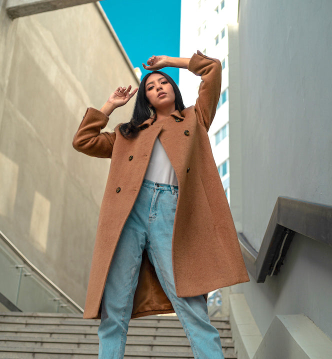 model wearing an alpaca camel coat with a city background