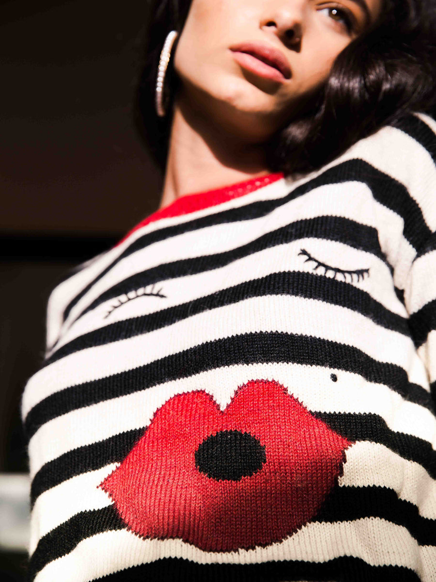 Person wearing a black and white striped sweater with red lips kiss design.