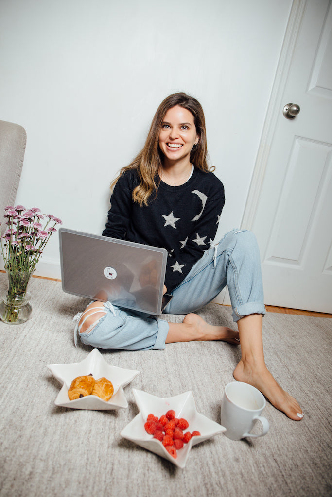 black baby alpaca knitted sweater with grey star and moon patterns, worn by a model sitting indoors on the floor