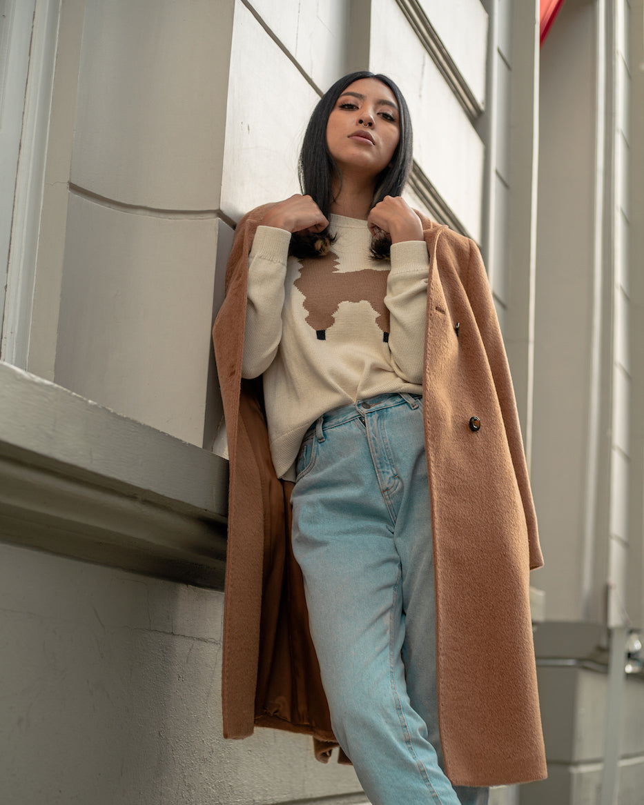 model wearing an alpaca camel coat with a city background